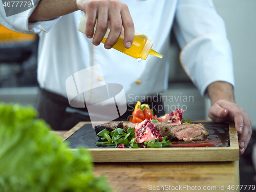 Image of Chef finishing steak meat plate