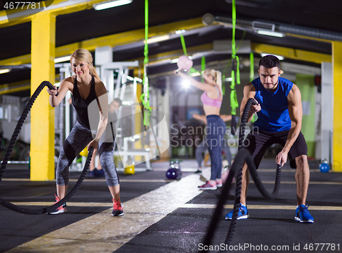 Image of sports couple doing battle ropes crossfitness exercise