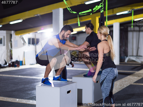 Image of athletes working out  jumping on fit box