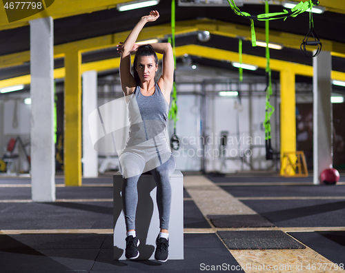 Image of woman warming up and stretching on fit box