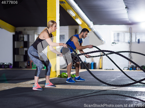 Image of sports couple doing battle ropes crossfitness exercise