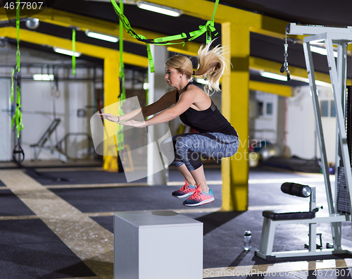 Image of woman working out  jumping on fit box