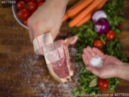 Image of Chef putting salt on juicy slice of raw steak