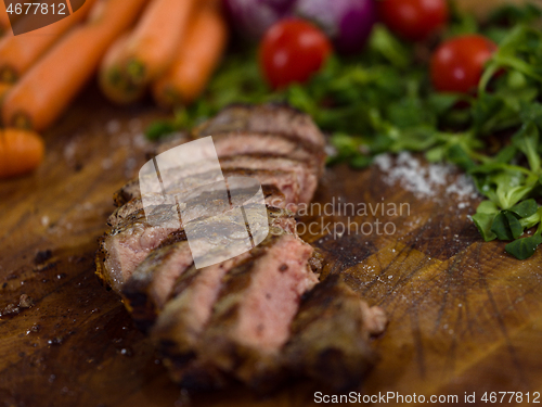 Image of Juicy slices of grilled steak on wooden board