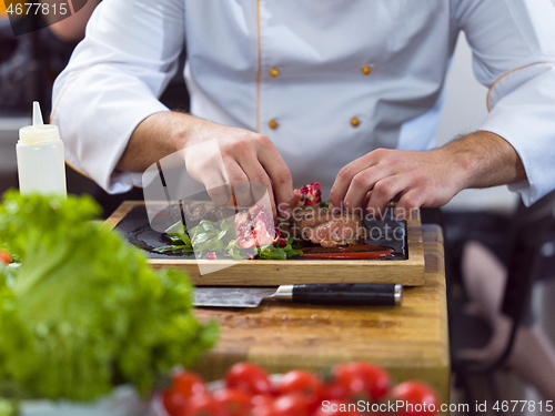 Image of closeup of Chef hands serving beef steak