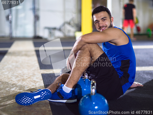 Image of young athlete man sitting on the floor and relaxing