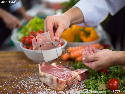 Image of Chef putting salt on juicy slice of raw steak