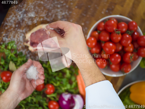 Image of Chef putting salt on juicy slice of raw steak