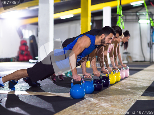 Image of young athletes doing pushups with kettlebells