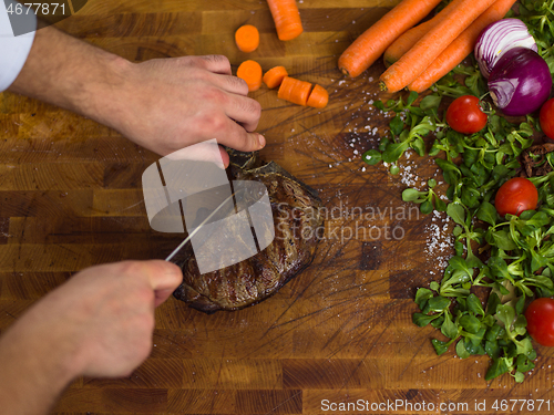 Image of closeup of Chef hands preparing beef steak