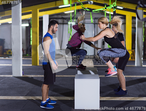 Image of athletes working out  jumping on fit box