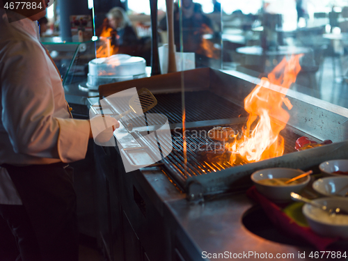 Image of chef cooking steak with vegetables on a barbecue