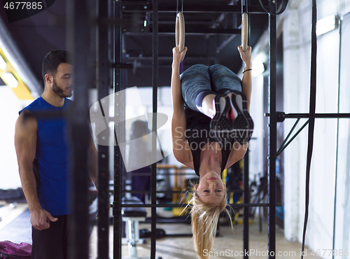 Image of woman working out with personal trainer on gymnastic rings