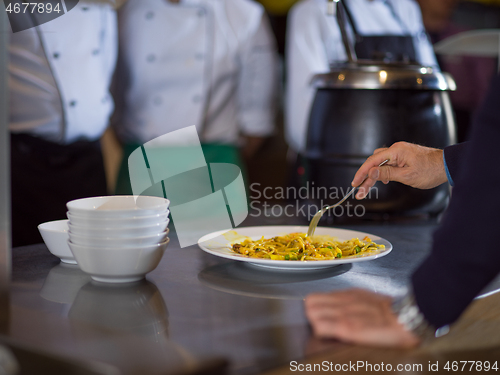 Image of chefs in the kitchen presenting dish of tasty meal