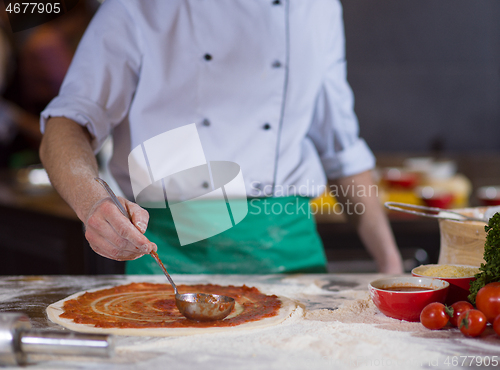 Image of Chef smearing pizza dough with ketchup