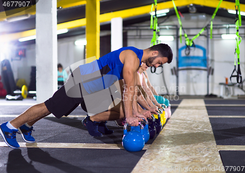 Image of young athletes doing pushups with kettlebells