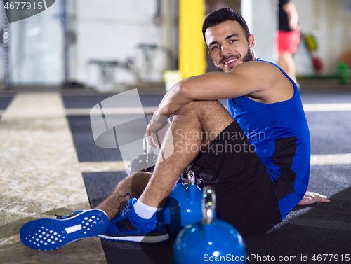 Image of young athlete man sitting on the floor and relaxing