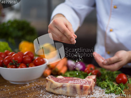 Image of Chef putting salt on juicy slice of raw steak