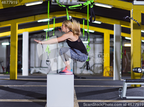 Image of woman working out  jumping on fit box