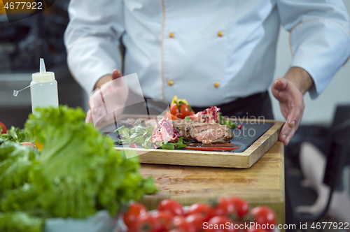 Image of closeup of Chef hands serving beef steak