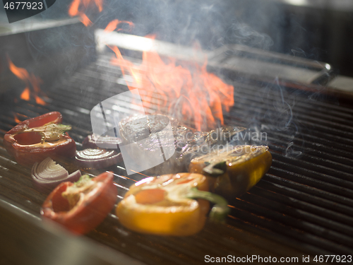 Image of chef cooking steak with vegetables on a barbecue