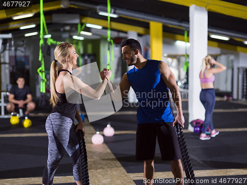 Image of sports couple doing battle ropes crossfitness exercise