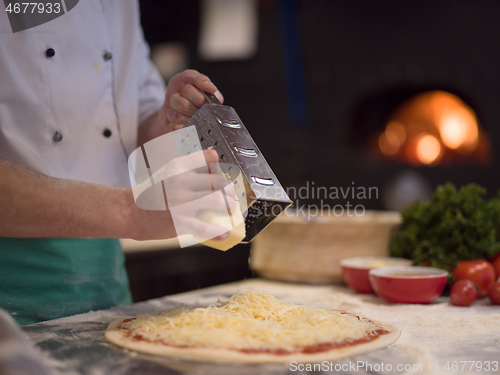 Image of chef sprinkling cheese over fresh pizza dough