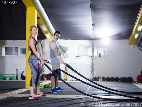 Image of sports couple doing battle ropes crossfitness exercise