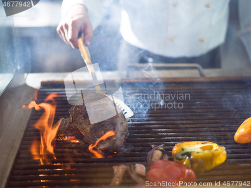 Image of chef cooking steak with vegetables on a barbecue