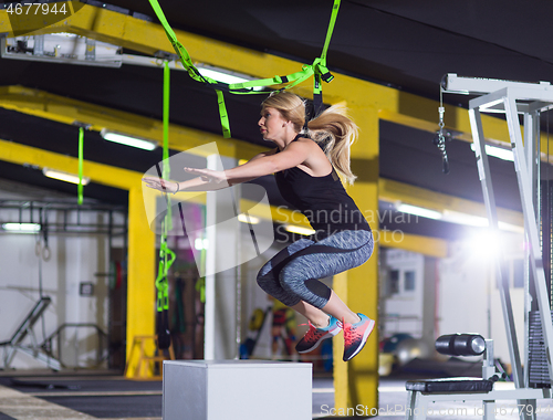 Image of woman working out  jumping on fit box