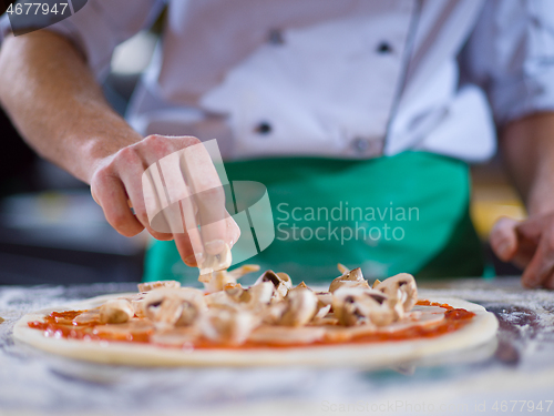 Image of chef putting fresh mushrooms on pizza dough