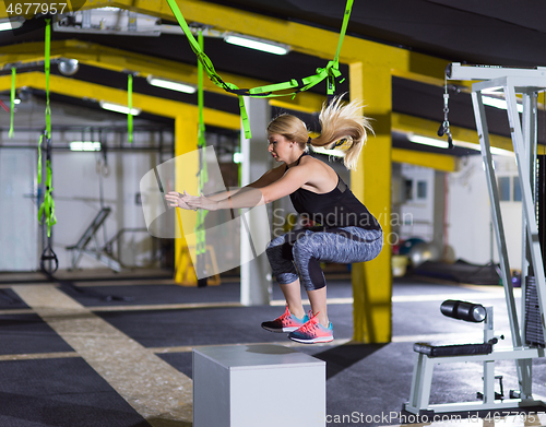 Image of woman working out  jumping on fit box