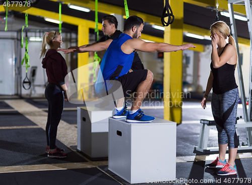 Image of athletes working out  jumping on fit box