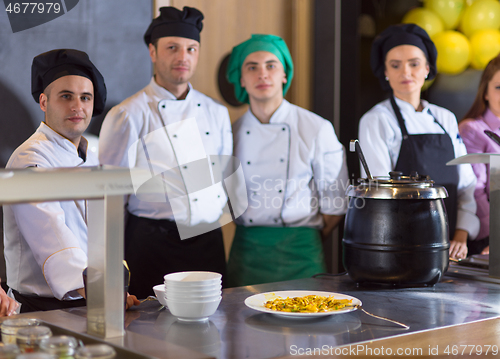 Image of chefs in the kitchen presenting dish of tasty meal