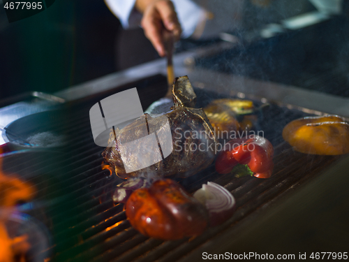 Image of chef cooking steak with vegetables on a barbecue