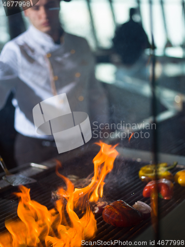 Image of chef cooking steak with vegetables on a barbecue