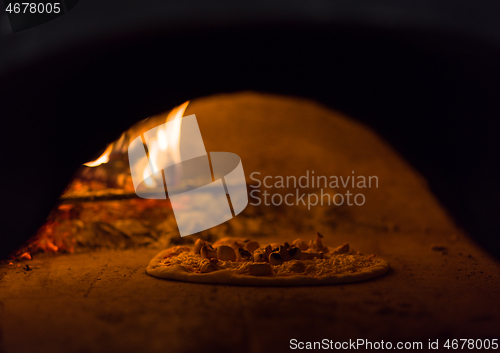 Image of chef putting delicious pizza to brick wood oven