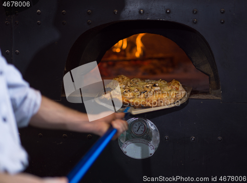 Image of chef removing hot pizza from stove