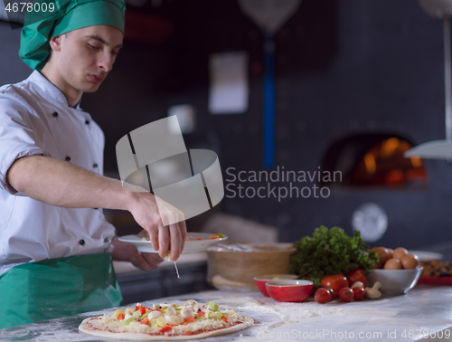 Image of chef putting fresh vegetables on pizza dough