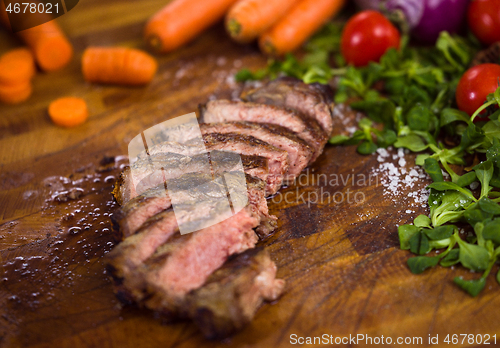 Image of Juicy slices of grilled steak on wooden board