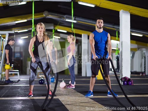 Image of sports couple doing battle ropes crossfitness exercise