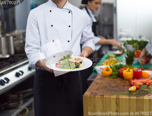 Image of Chef holding dish of fried Salmon fish fillet