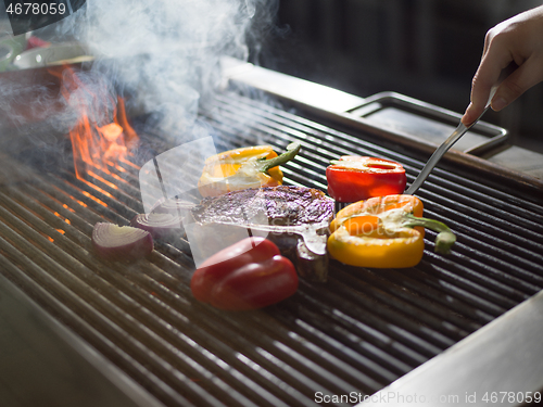 Image of chef cooking steak with vegetables on a barbecue