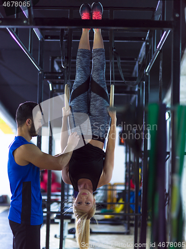 Image of woman working out with personal trainer on gymnastic rings