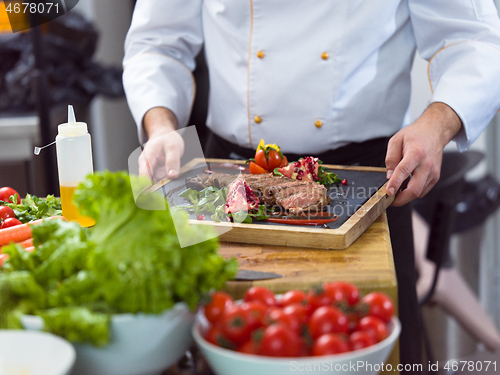 Image of closeup of Chef hands serving beef steak