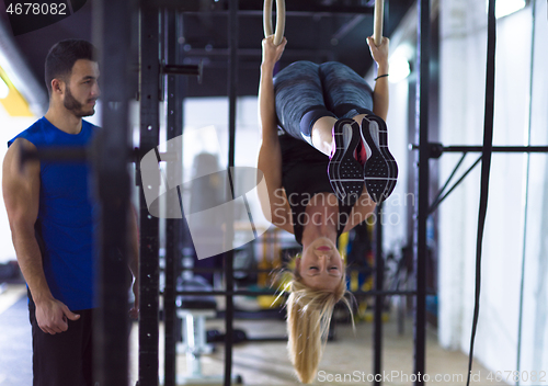 Image of woman working out with personal trainer on gymnastic rings