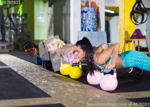 Image of young athletes doing pushups with kettlebells