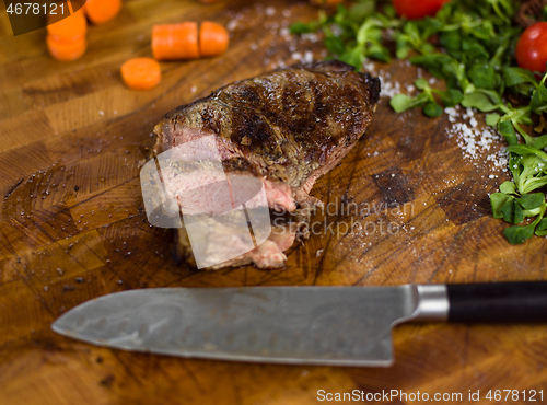 Image of Juicy slices of grilled steak on wooden board