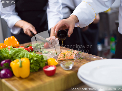 Image of Chef hands preparing marinated Salmon fish