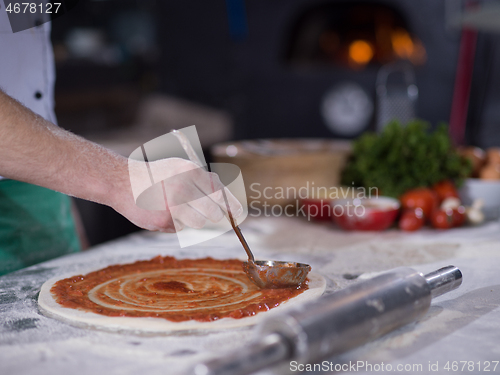 Image of Chef smearing pizza dough with ketchup